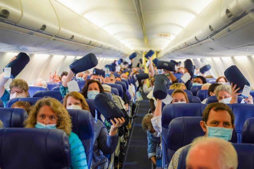 Surprised passengers display their gifts aboard their flight 